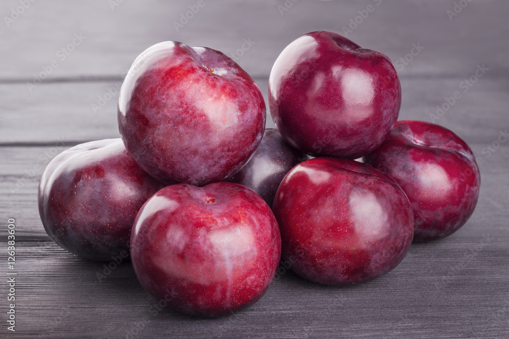 Ripe purple plums, on wooden background