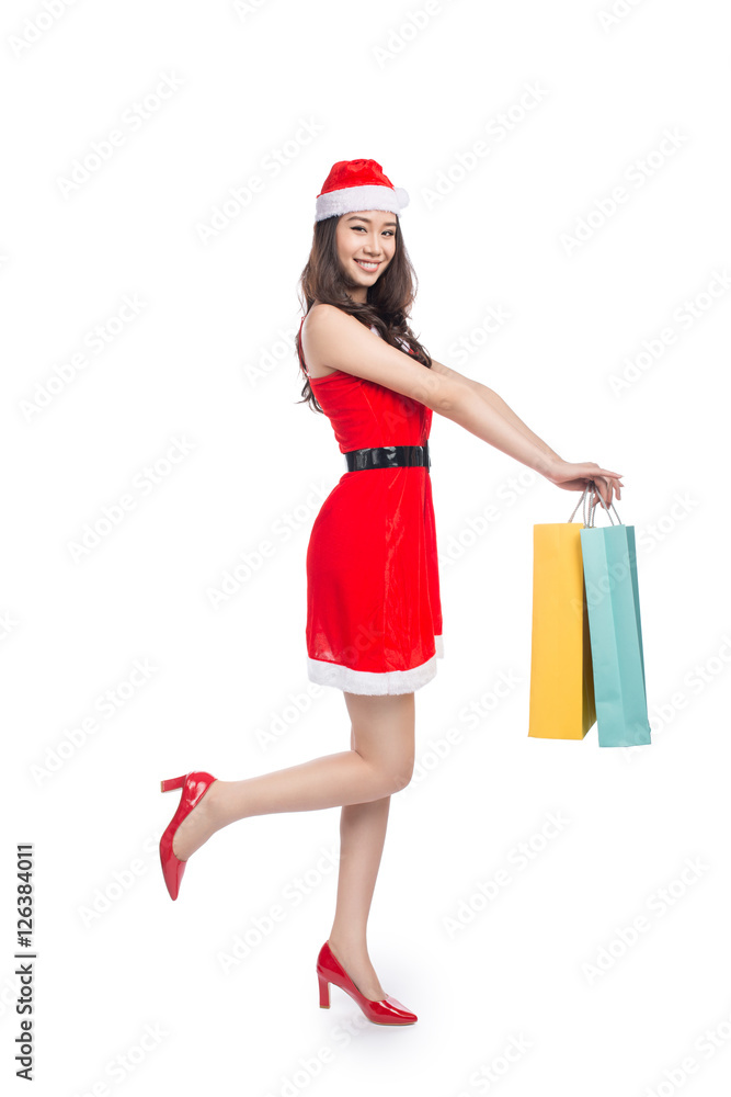 Full length portrait of a young smiling asian woman holding shopping bags before christmas Full length portrait of a young smiling asian woman holding shopping bags before christmas