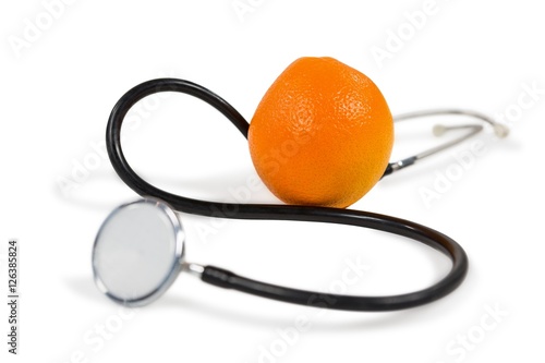 Stethoscope and orange on white background