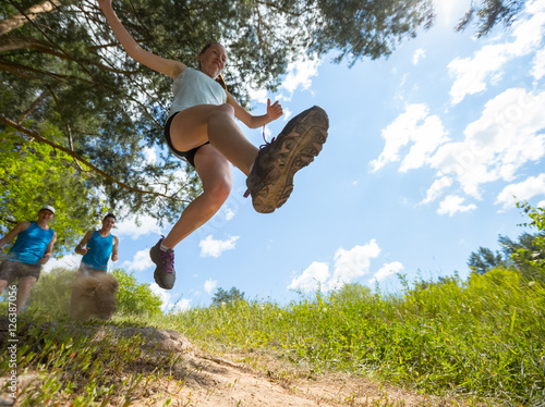 Trail running athlete jumping over camear at sunny day photo