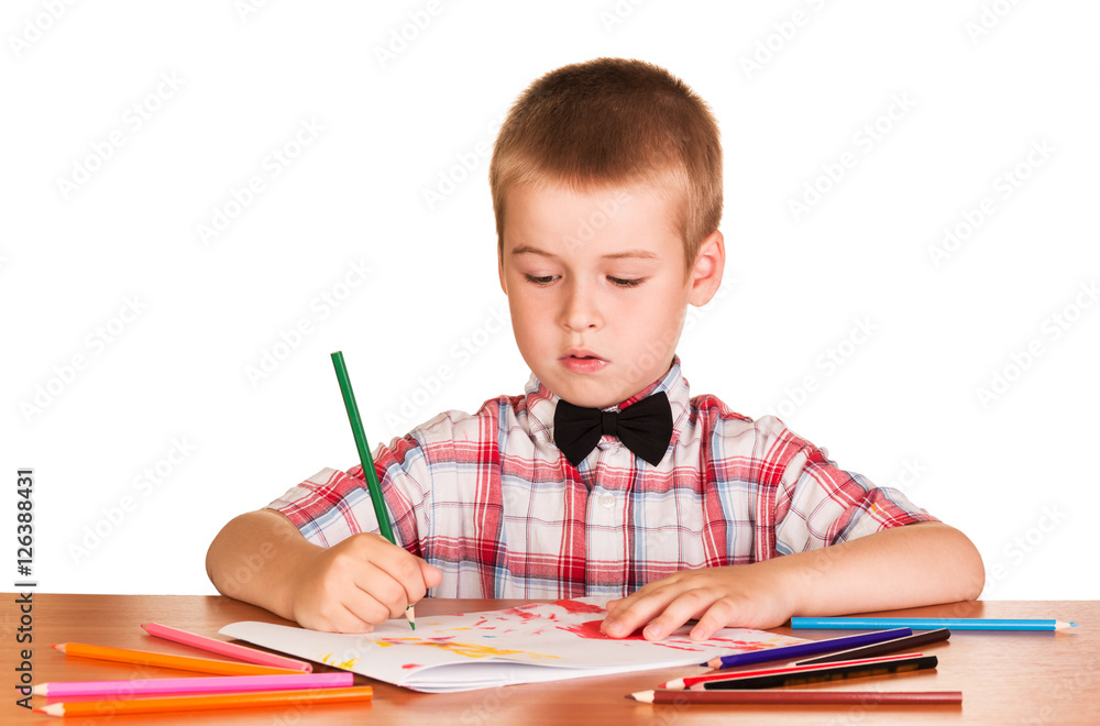 Cute schoolboy draws on the album with colored pencils isolated. Cute schoolboy draws on the album with colored pencils isolated.