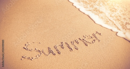 Summer written on sand with surf 