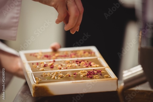 Worker sprinkling confectionary on chocolate mould