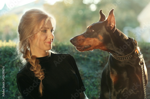 Fototapeta Portrait of beautiful young woman with her dog on blurred background