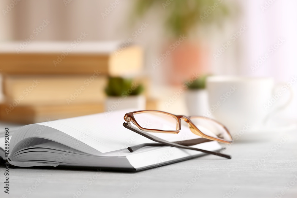 Glasses and notebook on wooden table. Healthy eyes concept Glasses and notebook on wooden table. Healthy eyes concept