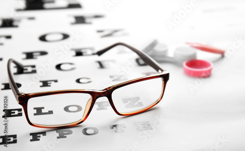 Glasses lying on eye test chart, close up view. Healthy eyes concept