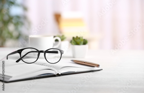 Glasses and open notebook on wooden table. Healthy eyes concept