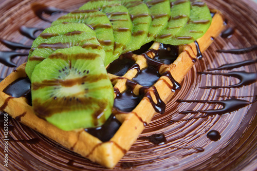 Plate of belgian waffles with kiwi  cream and chocolate