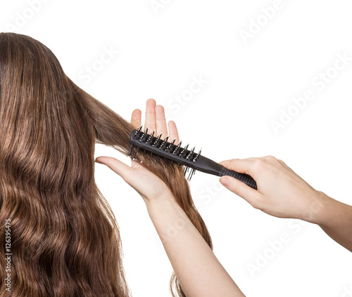 Hairdresser's hand combing long wavy hair isolated on white.