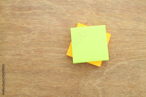 Stack of paper notes (white & yellow) on wood background, selective focus