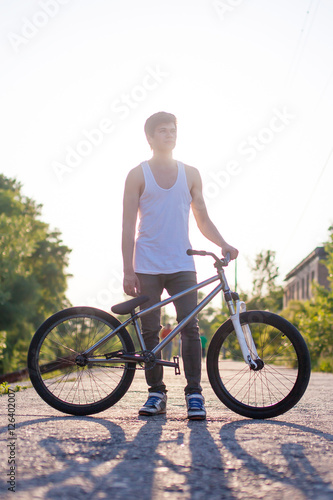 Fototapeta Naklejka Na Ścianę i Meble -  The boy hold his bike, photo at sunrise background