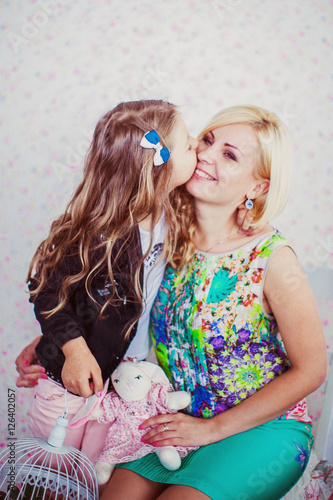 little cute girl and her mother sitting on chair