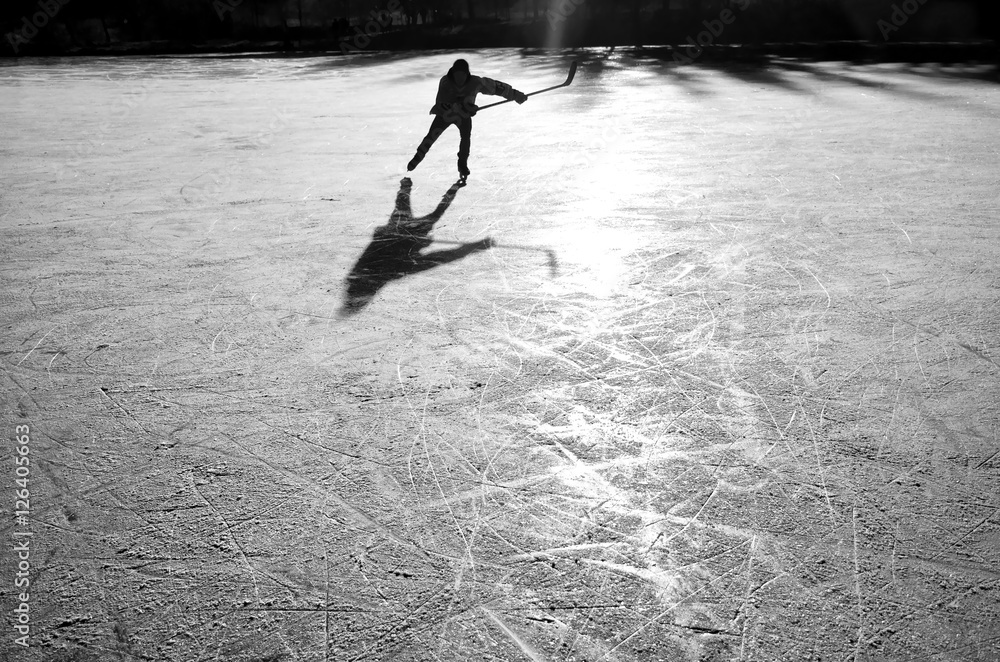 Fototapeta premium hockey player on the ice on sunset - black and white photo