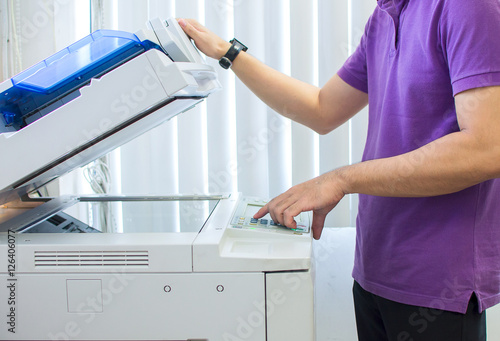 woman hands putting a sheet of paper into a copying device