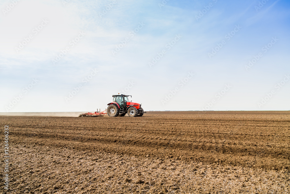 Farmer in tractor preparing land with seedbed cultivator Farmer in tractor preparing land with seedbed cultivator