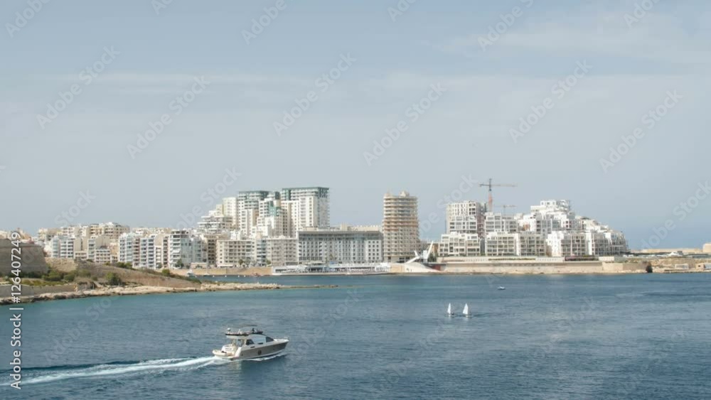 Boat ,Yacht sails in the background of Valletta in Malta. Wide shot, in the background of newly constructed houses. Boat ,Yacht sails in the background of Valletta in Malta. Wide shot, in the background of newly constructed houses.