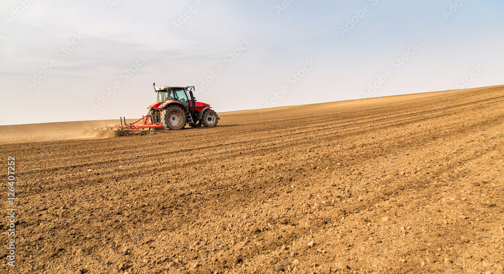 Farmer in tractor preparing land with seedbed cultivator Farmer in tractor preparing land with seedbed cultivator