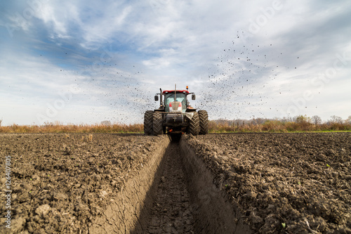 Tractor with double wheeled ditcher digging drainage canal