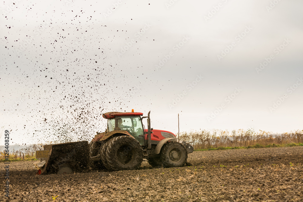Obraz premium Tractor with double wheeled ditcher digging drainage canal