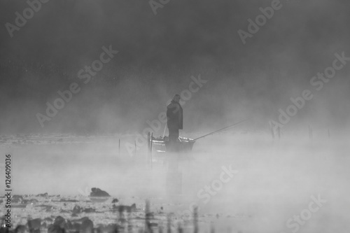 Fisherman in boat, foggy morning, misty atmosphere, silhouette