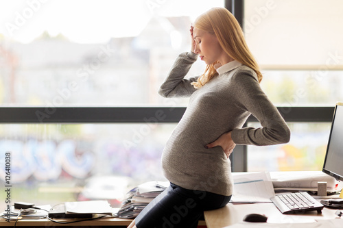pregnant businesswoman feeling sick at office work photo