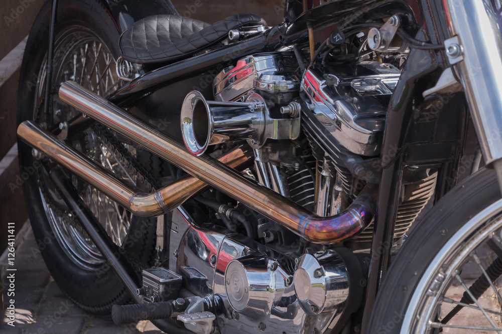 Motorcycle engine close-up. Chrome, shiny parts, wheels, exhaust.