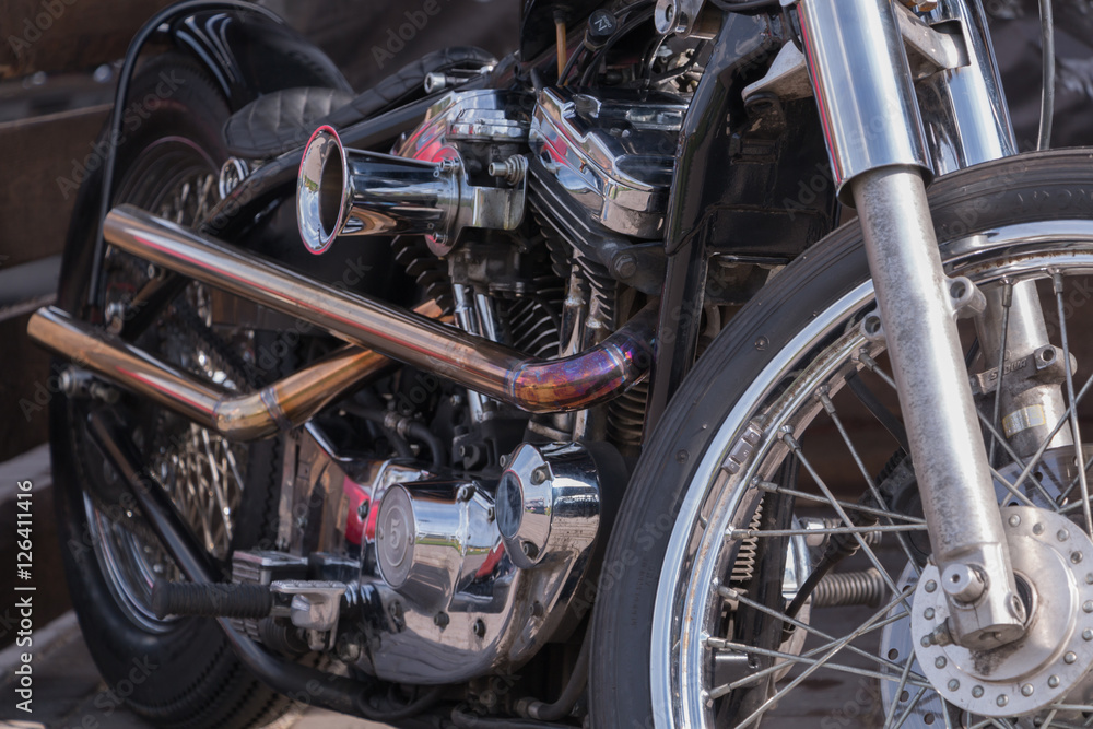 Motorcycle engine close-up. Chrome, shiny parts, wheels, exhaust.