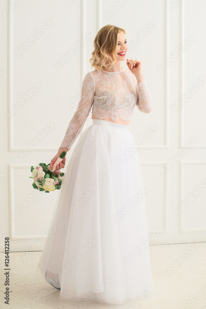 Beautiful bride standing with bouquet in a white room. Beautiful bride standing with bouquet in a white room.