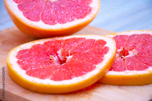 Sliced grapefruit on wooden cutting board. Fresh citrus close up