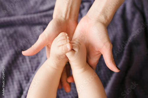 cute and little legs of newborn baby and hands of parents