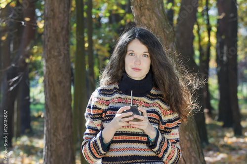 Young woman wearing knitted snowflakes pattern woolen sweater and holding hot yerba mate drink