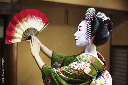 Woman dressed in traeditional geisha style, holding fan photo