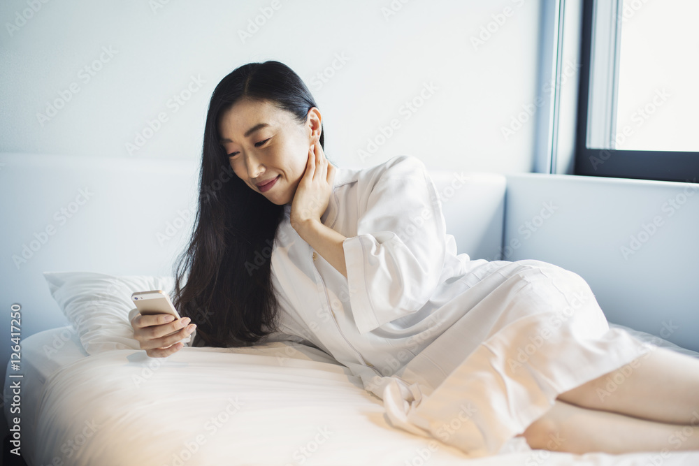 A business woman preparing for work, waking up and checking her smart phone in bed. A business woman preparing for work, waking up and checking her smart phone in bed.