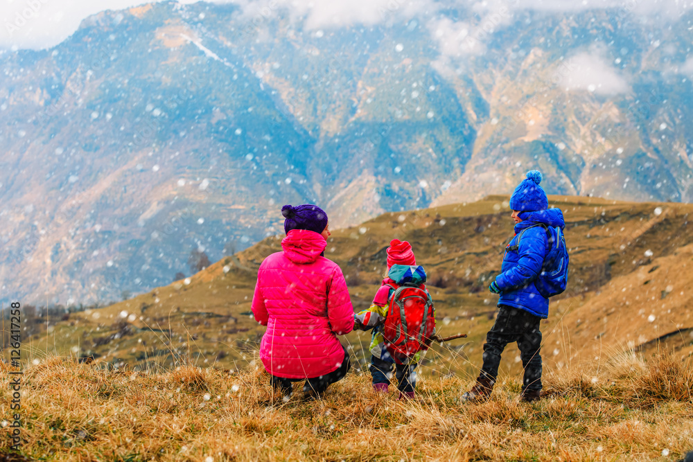 mother and two kids travel in winter mountains