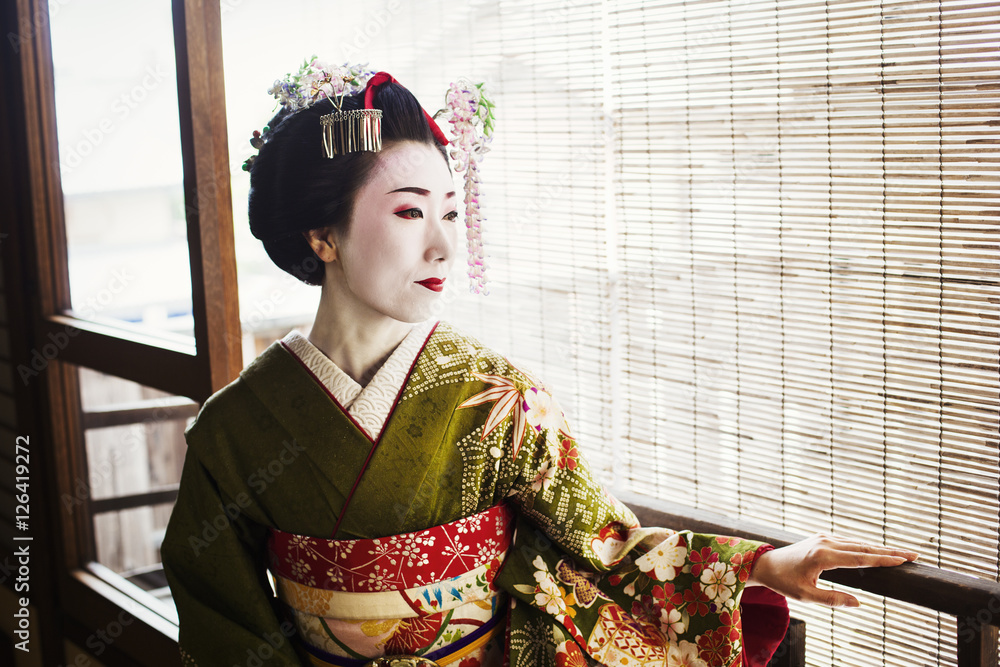 A woman dressed in the traditional geisha style, wearing a kimono and obi,  with an elaborate