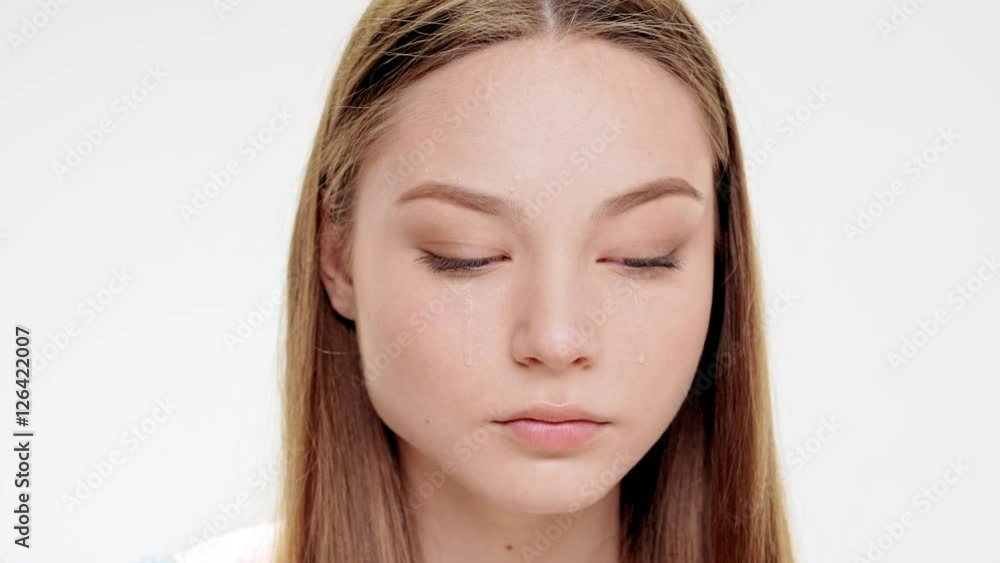 Sad young beautiful girl over crying white background. Slow motion. Sad young beautiful girl over crying white background. Slow motion.