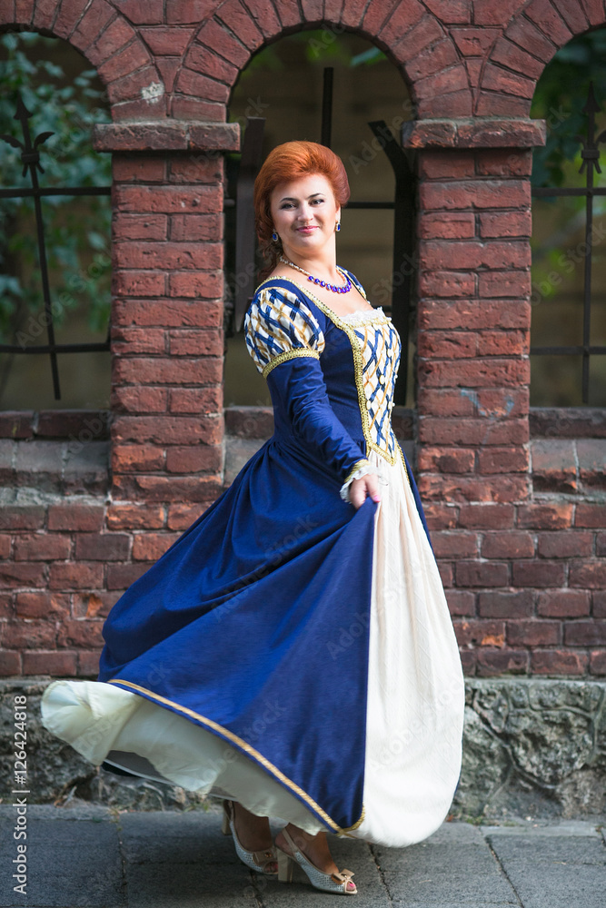 Naklejka premium Beautiful woman in medieval dress posing in old town