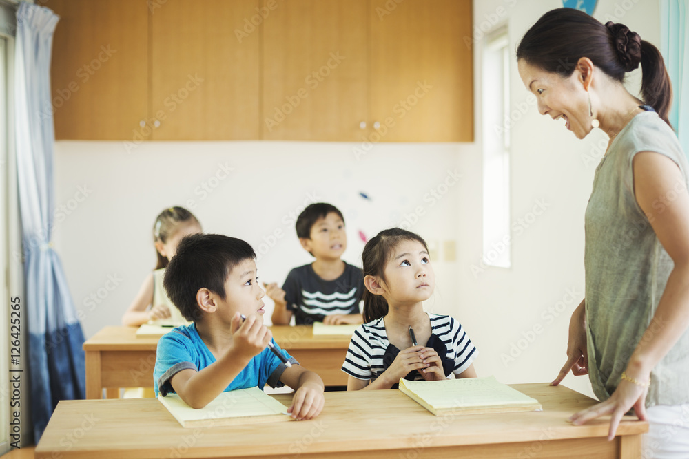 A group of children in a classroom with their female teacher. Stock ...