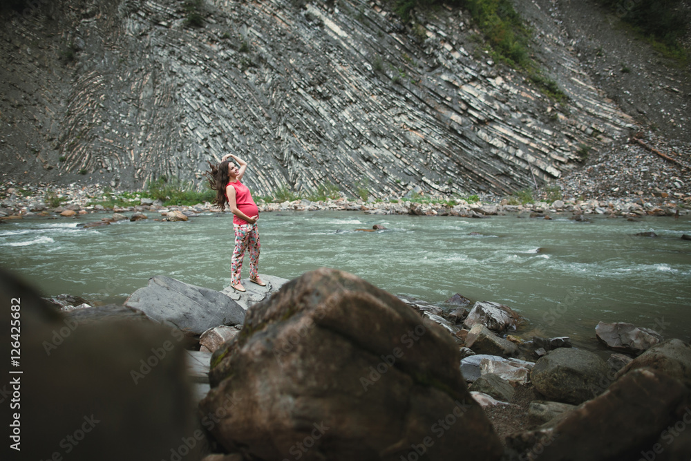 Beautiful pregnant woman posing near the river