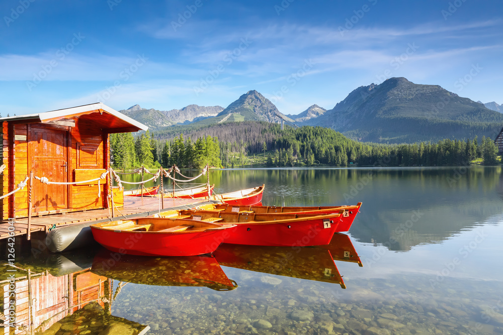 Dreamy red boats stand at the pier on a quiet lake.