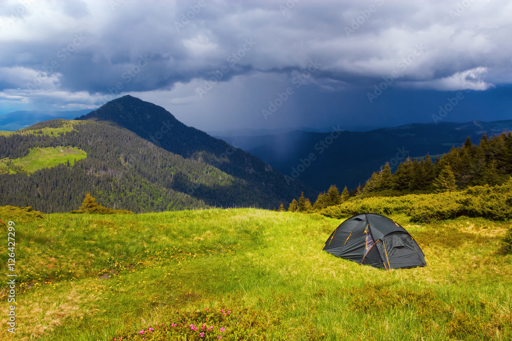 Opposite a high green mountain stands a tourist tent. Opposite a high green mountain stands a tourist tent.