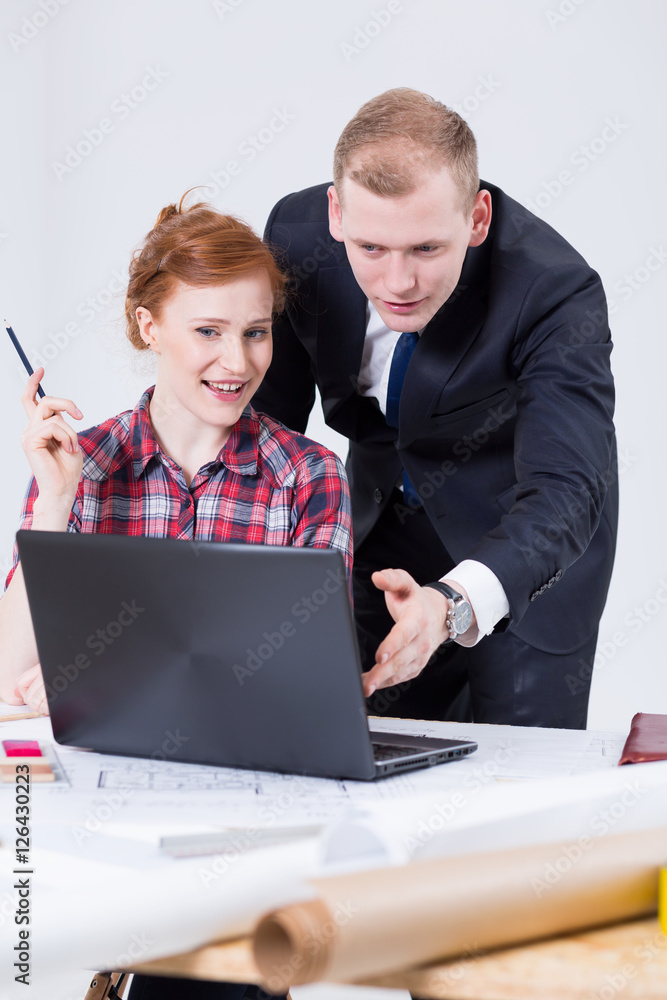 Womanand man sitting close to the drafting board in front of the laptop Womanand man sitting close to the drafting board in front of the laptop