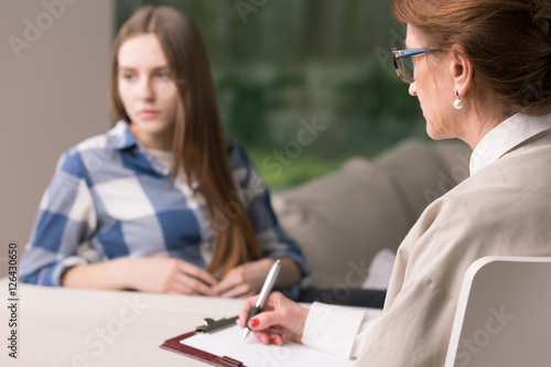 Depressed girl talking with a psychologist photo