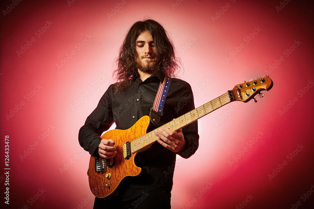 Obraz premium Ragazzo suona chitarra metal su fondo rosso