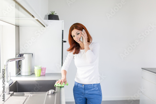 Junge Frau telefoniert bei der Hausarbeit