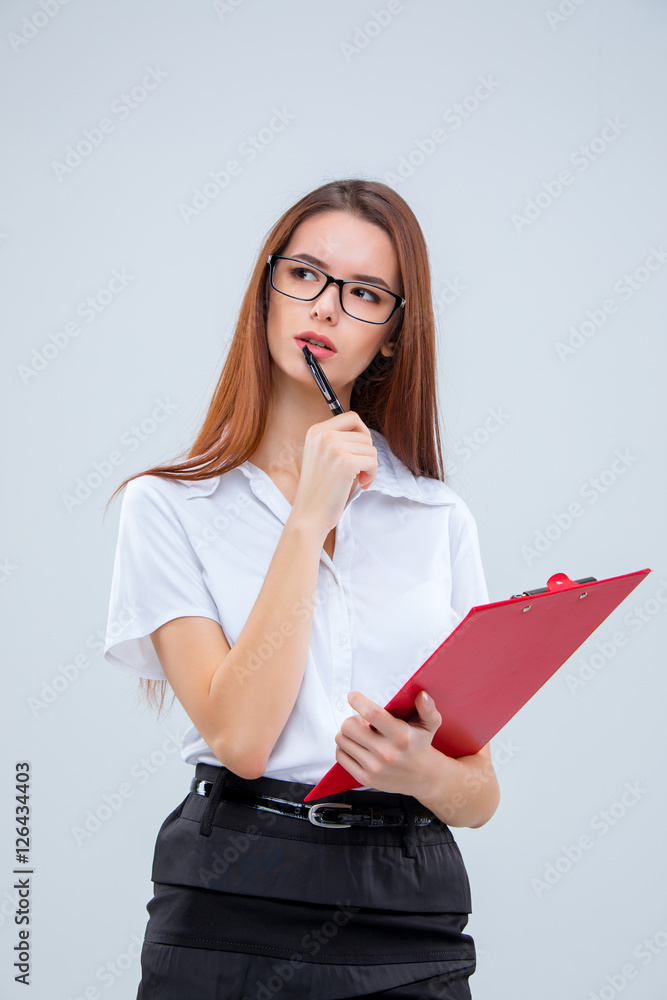 The young business woman with pen and tablet for notes on gray background The young business woman with pen and tablet for notes on gray background