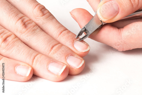 master of manicure cuts off the cuticle from the client fingers in nail salon