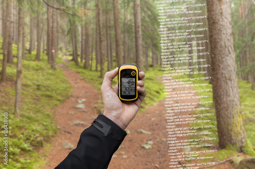 A trekker is finding the right position in the forest via gps in a cloudy autumnal day