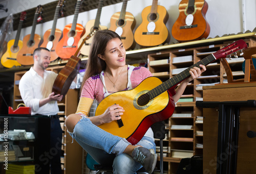 Couple playing guitars in music shop.