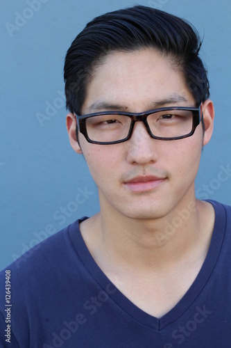 Asian man wearing glasses on a blue background - Stock image © ajr_images
